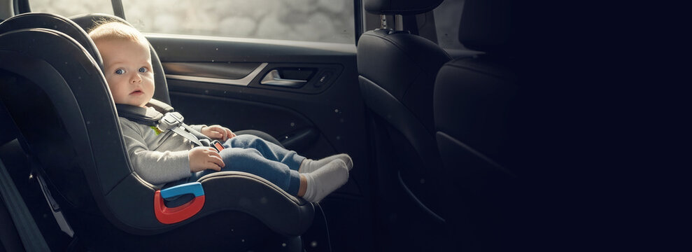 Baby sitting in child car seat inside vehicle. Safe travel for infant in secured seat. Protection and family transportation concept with little child during road trip by car. Banner with copy space