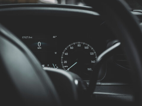 Car dashboard instrument cluster showing speedometer at 0 mph with digital display, fuel gauge and modern automotive interior detail
