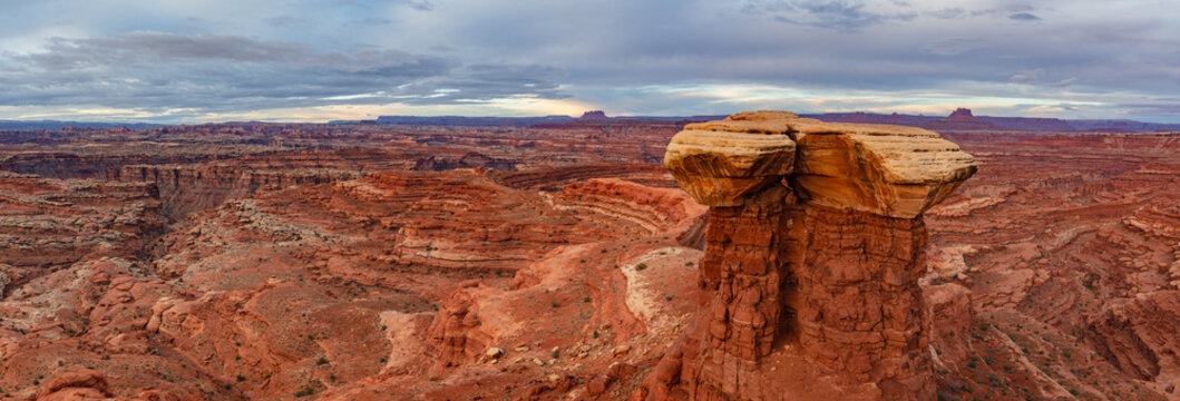 This scenic panorama of Canyonlands National Park features a lone rock formation surrounded by deep canyons.