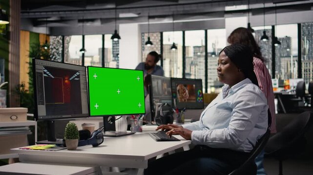 Green screen and video game software on dual monitors at the office, developer working with tools and assets to build a futuristic virtual world. Engineer developing gameplay mechanics.