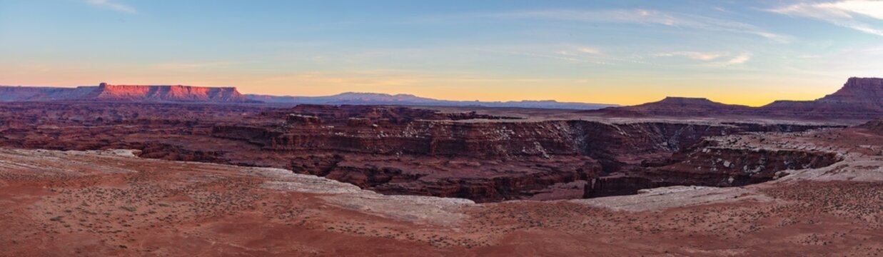 This scenic sunset panorama of Canyonlands National Park, Utah, features Gooseberry Canyon with the Needle District and Abajo Mountains (Blue Mountains) in the distance.