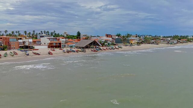 Drone shot over turquoise ocean toward Northeast Brazil's coastal fishing village.