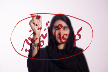 Obraz premium Woman writing Arabic New Year greeting on glass with red marker in festive calligraphy