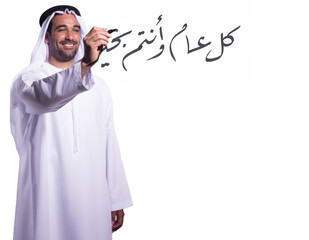 Obraz premium Smiling Arab man in traditional kandura writing Arabic calligraphy greeting for Eid and New Year celebration