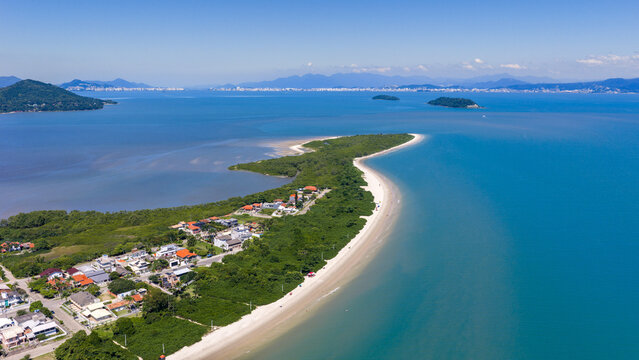 Idyllic aerial perspective of Praia da Daniela's slender white sandbar embraced by calm crystal-clear waters in Florianopolis.