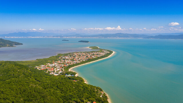 Panoramic aerial view of Praia da Daniela with curved sandy shore and calm turquoise sea in Florianopolis.