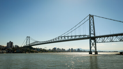 Fototapeta premium Panoramic view of Hercílio Luz Bridge in Florianopolis Brazil crossing wide bay toward distant city skyline.