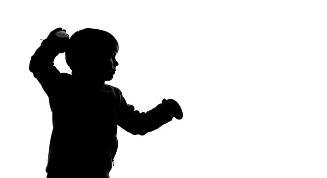 A silhouette of a young boy throwing a punch in a dynamic pose