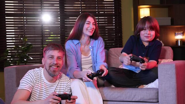 Happy family with controllers playing video game on sofa at home