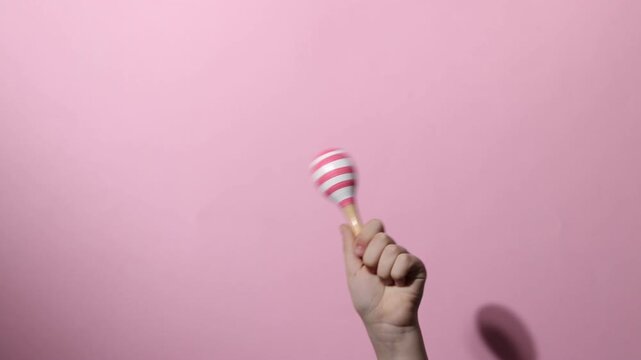 Child with toy maraca on pink background, closeup
