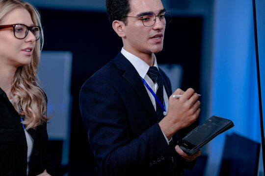 Code breakthrough achieved. Smiling senior developer points to a successful code segment on screen, sharing the solution with his colleague during a late night pair programming session.