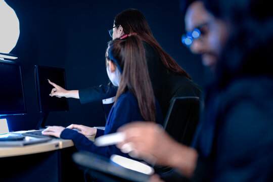 Focused female professionals collaborating late night in modern tech hub. Team members analyze data review designs pointing at screen typing notes on tablet intense project grind.