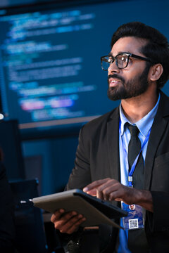 An Indian male tech leader or consultant presents a new digital strategy. He holds a tablet, discussing AI innovation, data analytics, and sustainable ESG goals at a summit.