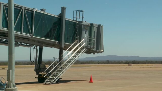 Airport Jet Bridge at Terminal Gate on Empty Tarmac under a clear blue sky.