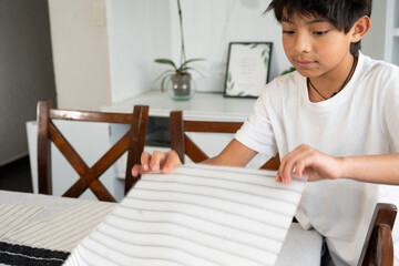 Naklejka premium Young Mexican boy setting the dining table for family lunch