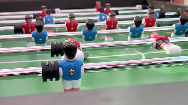 Horizontal close up video. Plastic people players figures, blue versus red team in table football soccer match with ball. Concept of sport, championship, board game, hobby, teamwork, win, home play