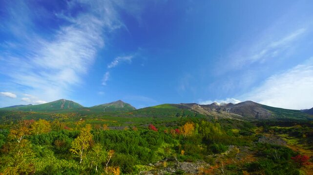 望岳台から望む十勝連峰と大雪山と紅葉の樹林と秋空