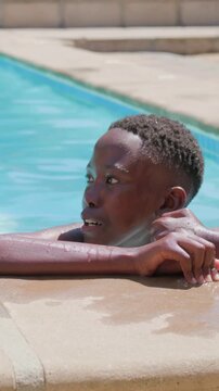 Vertical video: Turning teen shirtless at pool edge, rubbing face and smiling at adult appearing