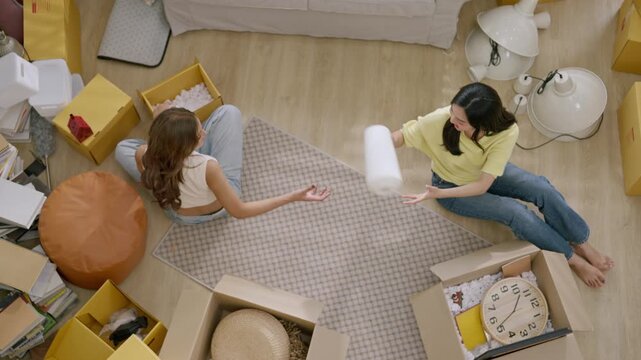 Moving packing box apartment women overhead view relocation cardboard living room home organization, friends unpacking cardboard boxes on floor in new home, cheerful roommates organizing during move