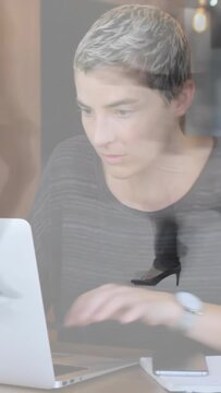 Vertical video: Worker placing hands on laptop while typing, heels moving across frame, tech work