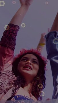 Vertical video: Woman in pink crown raising arm and singing sparking festival joy bubbles floating