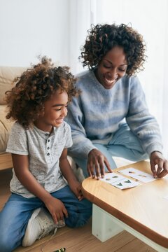 Speech therapist working with a young child using flashcards on a wooden table, supportive educational session for early childhood development and learning marketing