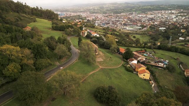 Historic ancient stone palace building in countryside village on green mountain slopes aerial view.
