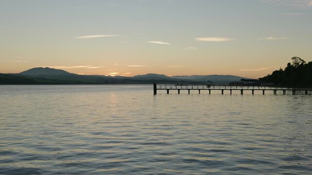 The sun rises over the calm waters and distant hills of Tomales Bay