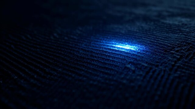 Digital blue light textured surface emitting subtle glow and futuristic mood closeup detail of ripple pattern and reflective threads dark textured fabric with subtle blue light reflection moody