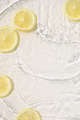 Naklejka premium Fresh yellow lemon slices floating in clear water with ripples texture.