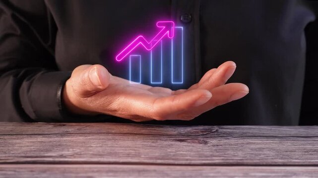 Business expansion and development. Close-up of a woman's hand on a table holding a virtual bar graph icon with an upward-pointing arrow.
