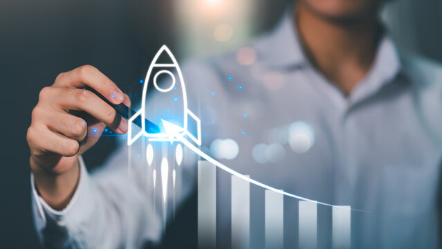 A person draws a rocket launching upward alongside a rising bar chart, symbolizing startup growth, business acceleration, performance metrics, innovation strategy, exponential success driven by data