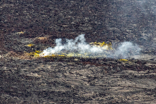Close up of yellow sulfur deposits and steam venting from a lava field in Hawaii Volcanoes National Park Big Island Hawaii
