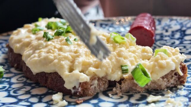 Cutting Open faced egg salad sandwich on a plate
