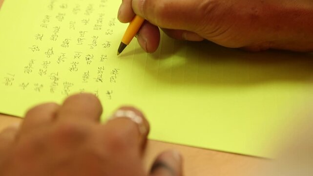 한국의 실내에서 노란색 편지지에 볼펜으로 정성스럽게 글씨를 쓰는 손 모습 근접 촬영 핸드헬드 브이로그 영상
