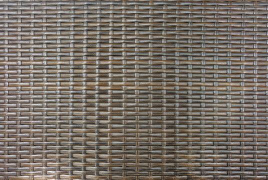 Dark Brown Synthetic Rattan Weave Texture for Furniture and Interior Design Background. Dark brown, plastic, rattan wicker pattern features an interlocking weave that provides modern, durable texture