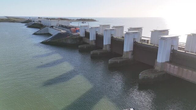 Drone pulls back from the lock complex with the Afsluitdijk extending behind it toward the distant horizon.