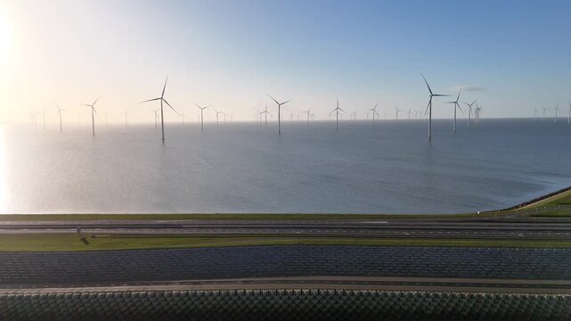 Drone pulls back from the dam over the North Sea side and reveals wind turbines standing in the IJsselmeer.