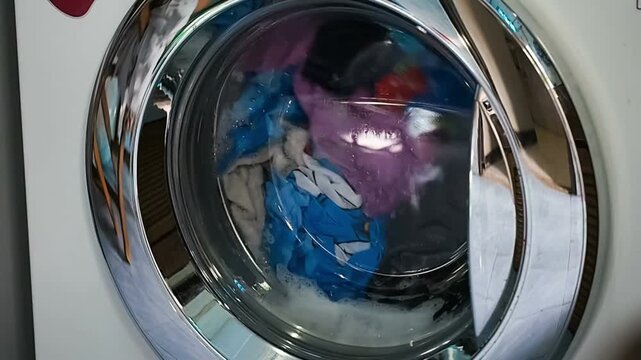 closeup working laundry machine spinning cleaning colorful cloth colored tumbling clothing soap