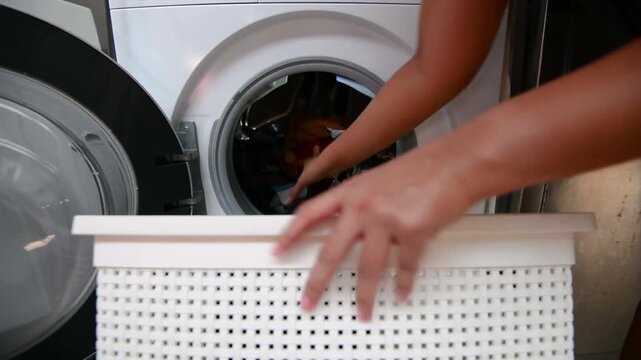 person unloading and loading clean cloth after doing cleaning laundry in machine washer