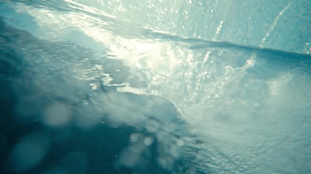 Underwater ocean turbulence vortex barrel with bubbles rising beneath breaking wave, slow motion