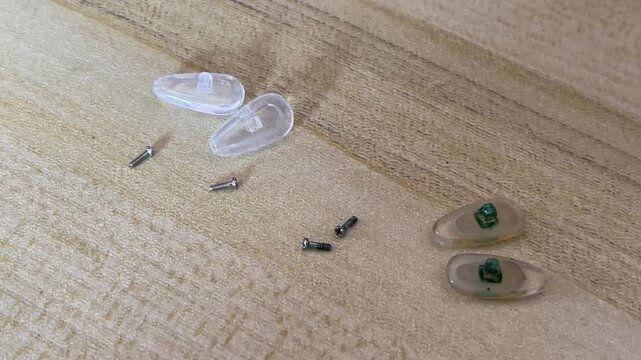 A detailed panning shot showing the contrast between new clear airbag nose pads and old yellowed ones with green moss like oxidation on a wooden surface during a home DIY project.