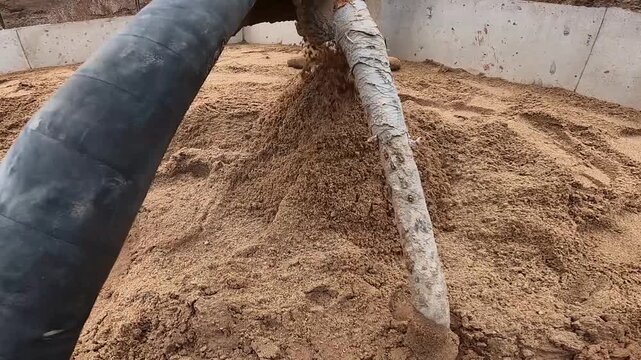 Concrete pump hose filling foundation area with sand inside formwork, preparing for concrete floor.