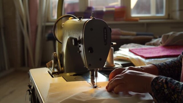 Artisan Craft: Capturing the Moment of a Seamstress Skillfully Sewing Fabric with a Vintage Sewing Machine in a Cozy Workshop Setting