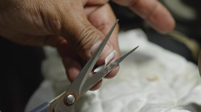 Craftsman testing scissors sharpness by cutting cloth