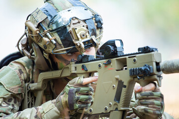 Fototapeta premium Two Soldiers Collaborating on Tactical Operations with Assault Rifles in a Camouflaged Environment, One Soldier Wearing a Green Assault Rifle and Camouflage Gear, Observing with a Red Sight, Preparing
