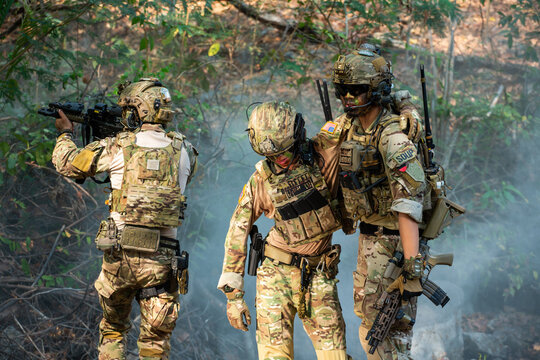 U.S. Military Personnel Conduct Tactical Training in Dense Foggy Forest with Camouflage Gear and Weapons, Three Soldiers Wearing Helmets Walking Through Dense Woods Carrying Firearms and Vests.