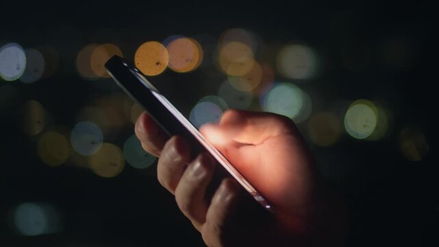 Male hand scrolling smartphone feed late at night with blurred city lights. Digital addiction concept shows smartphone addiction compulsive scrolling social media overuse and night routine.