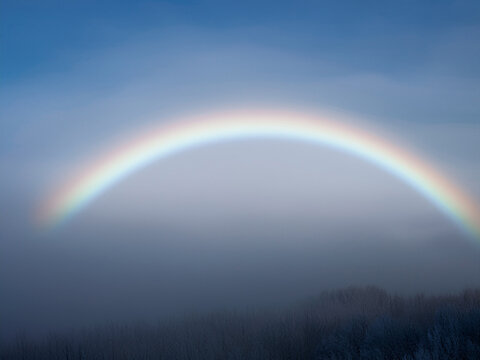 fogbow forming a wide pale white rainbow arc in dense fog