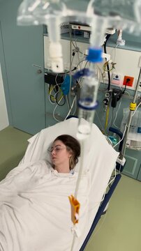Patient lying in hospital bed with IV drip and medical equipment. Concept for treatment, monitoring, and healthcare.
